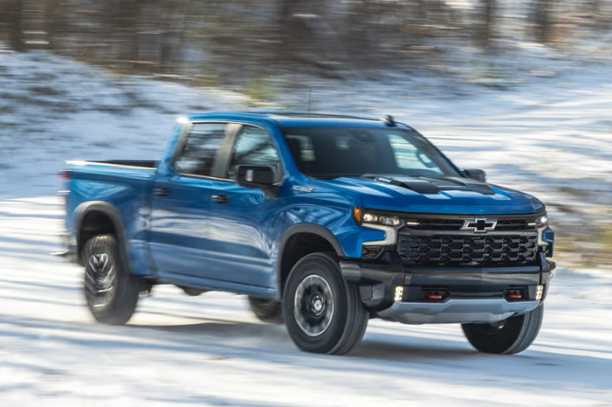 a chevrolet truck driving on a snowy road
